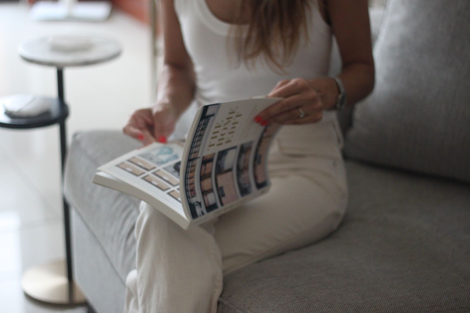 Woman reviewing interior styling magazine on a neutral-toned sofa – representing thoughtful Airbnb styling in Dubai