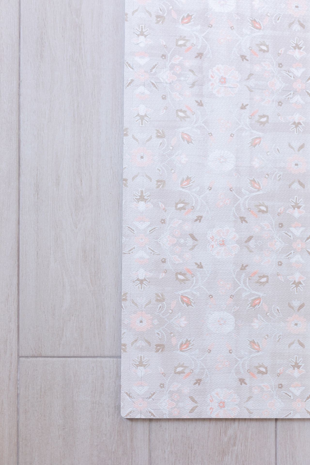 Close-up of a floral patterned rug on a light wood floor.