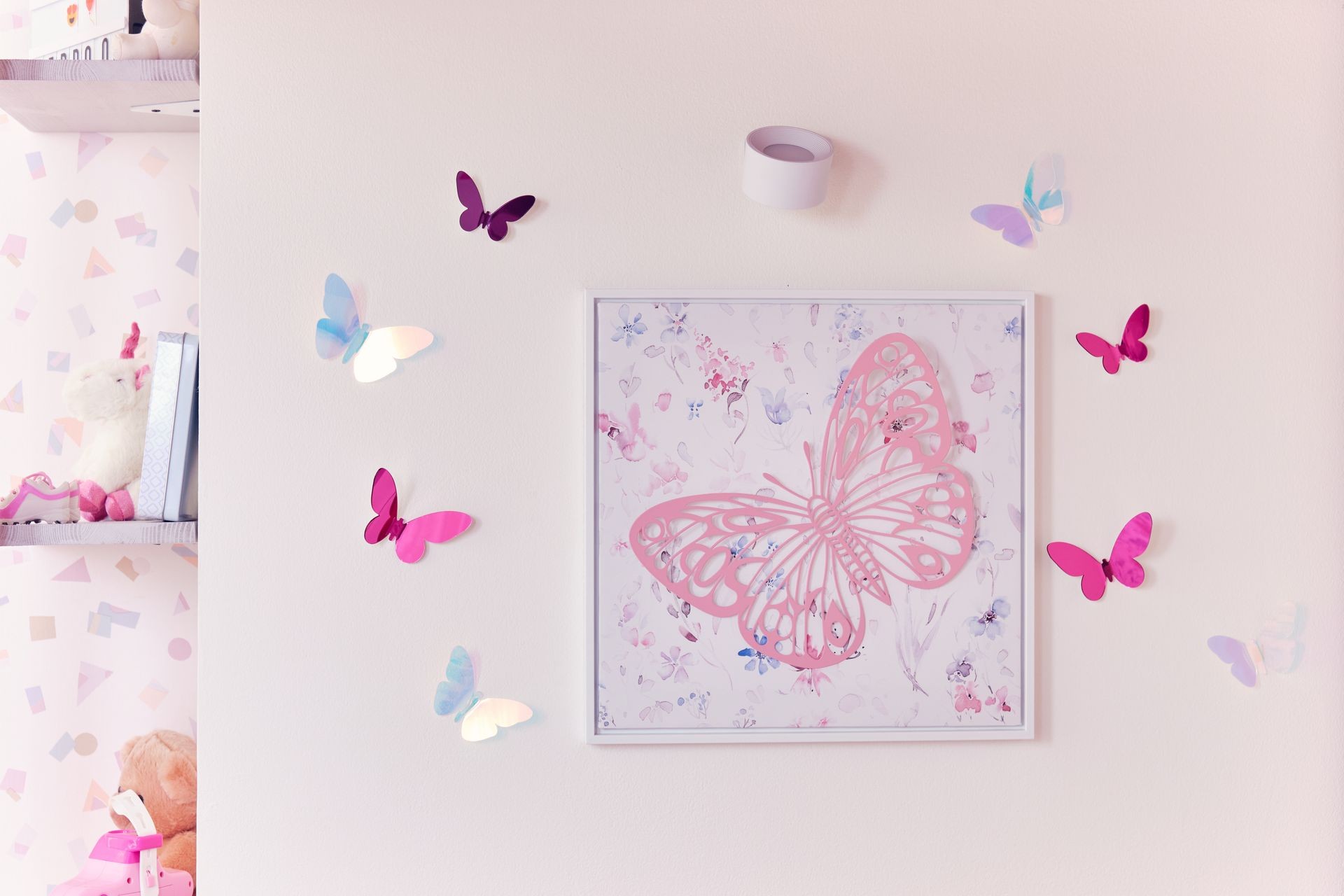 Decorative wall art with butterfly designs and pastel-colored accessories in a children's room.