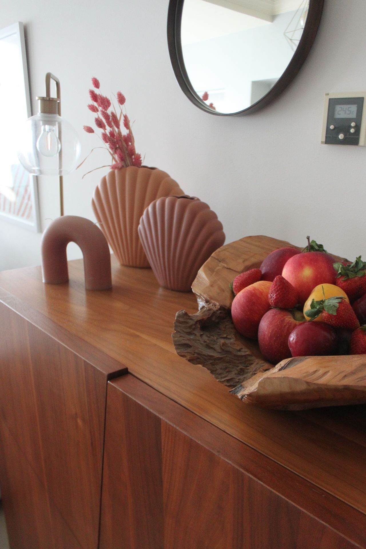 Close-up of a styled wooden console with organic vases, dried florals, and a rustic fruit bowl — showcasing natural textures and thoughtful finishing touches for a warm guest experience.